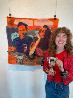 Emily holding trophy in front of painting of two people